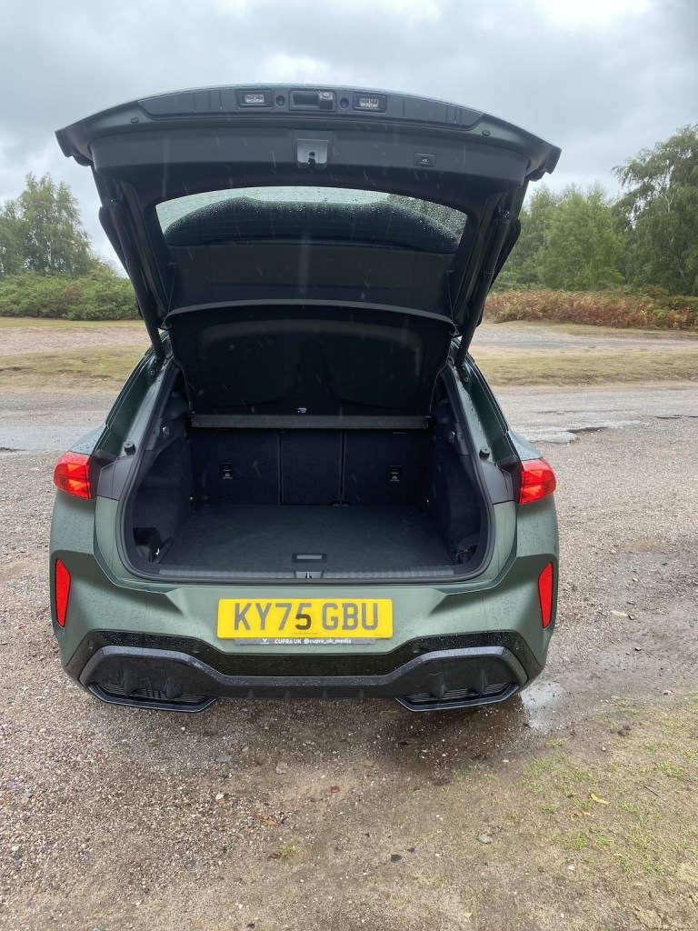 View of an open car trunk showing a spacious interior, set against a cloudy outdoor backdrop.